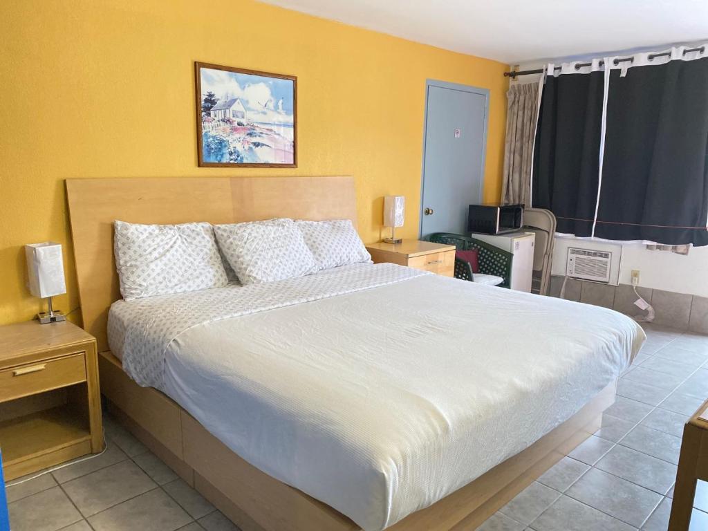 Locust ValleyTides Inn at Stehli Beach的卧室设有一张白色大床和黄色的墙壁