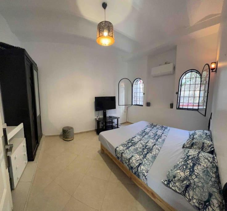 艾因埃尔特克Magnifique Villa avec garage à 2min de la plage Saint-Rock, Ain El Turk, Oran的一间卧室设有一张床、一台电视和两个窗户。