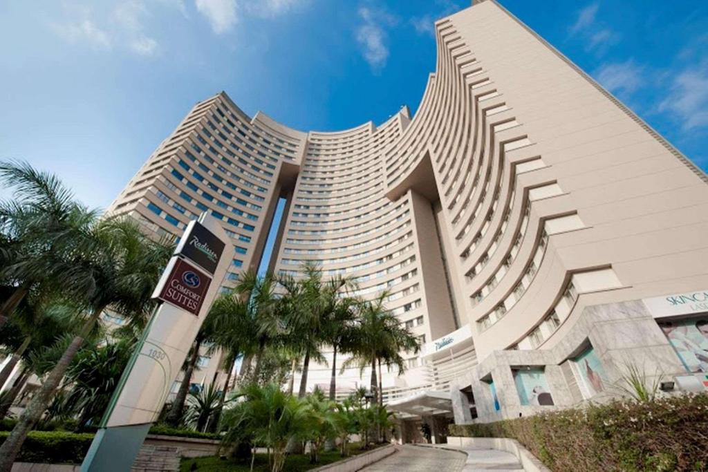 巴鲁埃里阿尔法城丽笙酒店的一座棕榈树环绕的大建筑