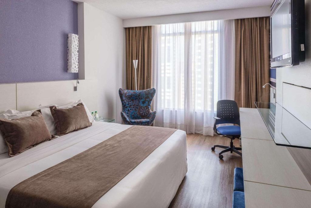 库里提巴拉迪森库里蒂巴酒店的配有一张床和一把椅子的酒店客房