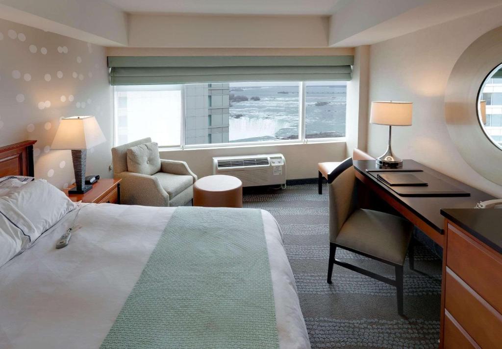 尼亚加拉瀑布丽笙及套房福尔斯维尤酒店的配有一张床、一张书桌和一扇窗户的酒店客房