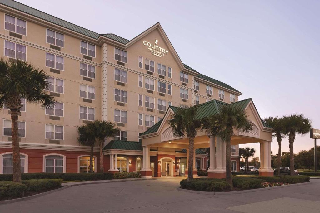 奥兰多Country Inn & Suites by Radisson, Orlando Airport, FL的一座酒店大楼前面有棕榈树