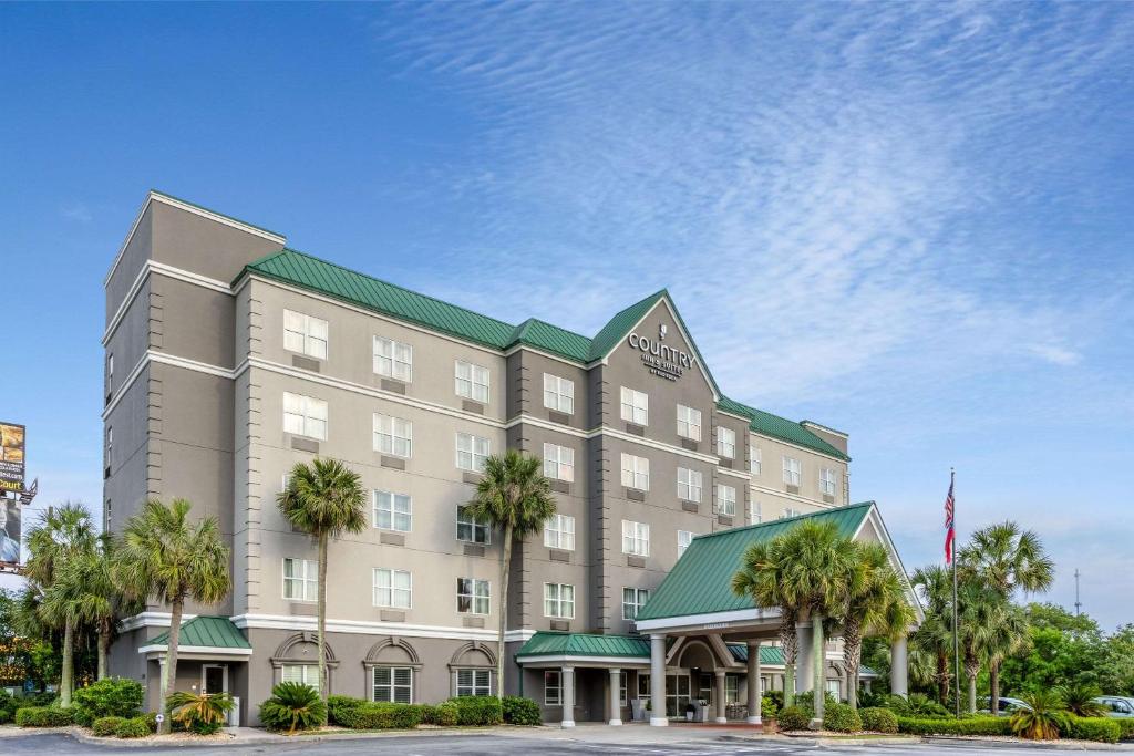 瓦尔多斯塔Country Inn & Suites by Radisson, Valdosta, GA的棕榈树酒店前的 ⁇ 染