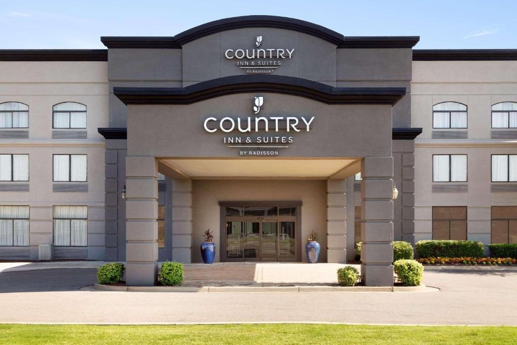 孟菲斯Country Inn & Suites by Radisson, Wolfchase-Memphis, TN的一座拥有进入县旅馆和套房入口的建筑