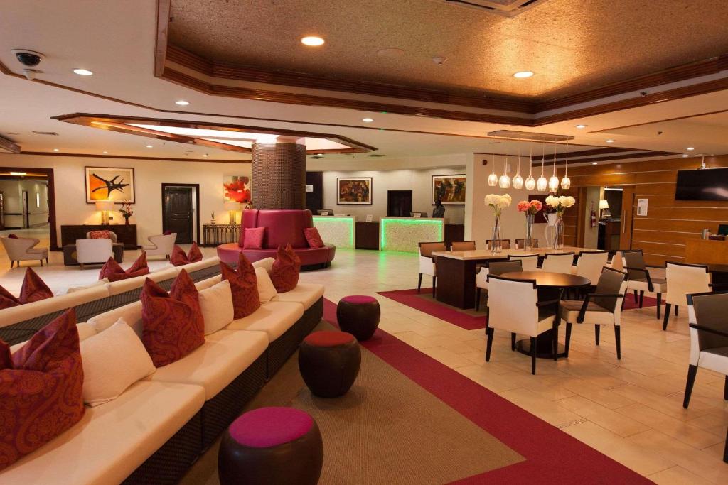 西班牙港特立尼达丽笙酒店的酒店大堂设有沙发和桌子,还有一间用餐室