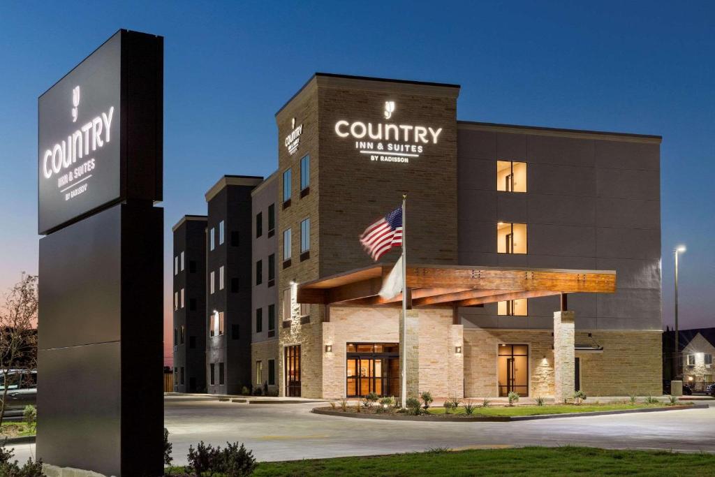 新布朗费尔斯Country Inn & Suites by Radisson, New Braunfels, TX的前面有美国国旗的建筑