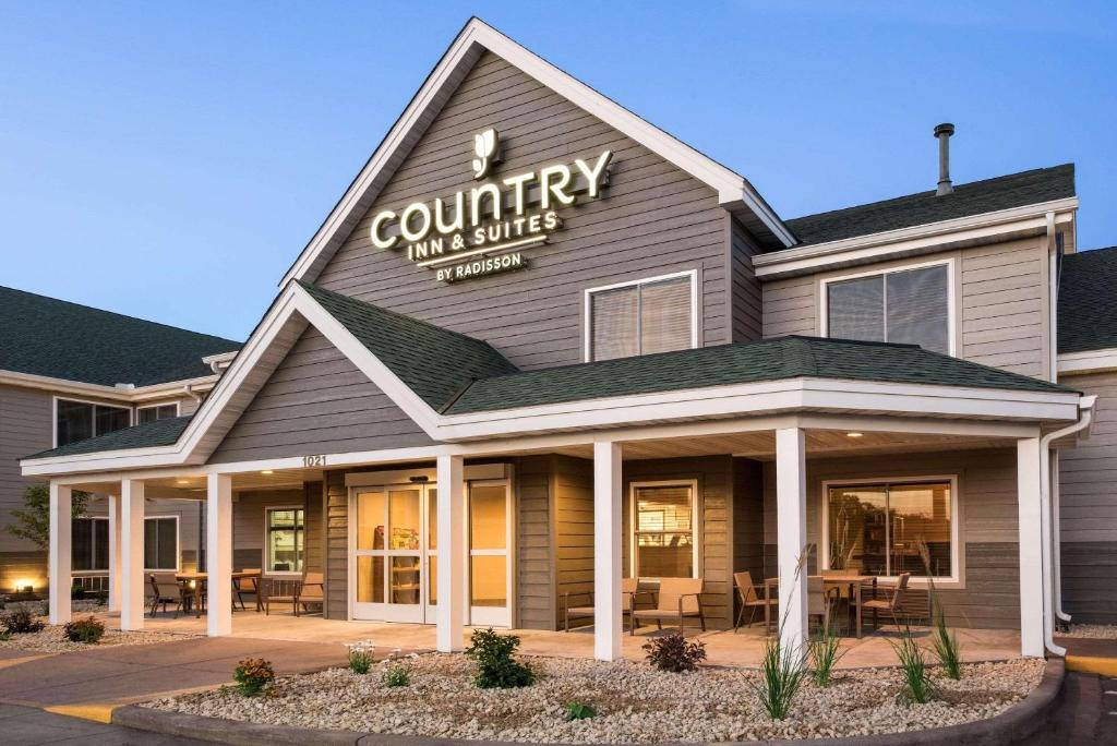 奇珀瓦福尔斯Country Inn & Suites by Radisson, Chippewa Falls, WI的乡村旅馆和套房大楼,配有桌椅
