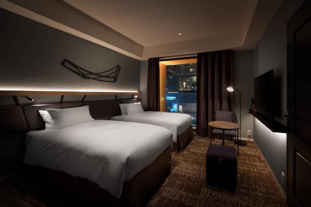 大阪Nest Hotel Osaka Umeda的酒店客房设有两张床和窗户。