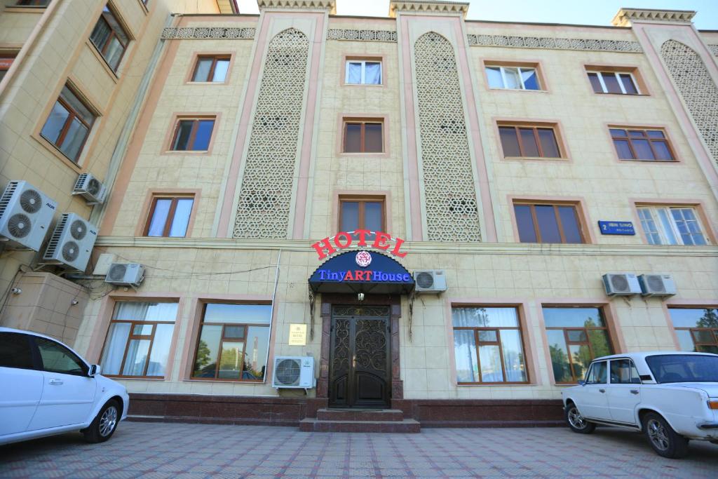 撒马尔罕TINY ART HOUSE HOTEL near Airport of Samarkand的两辆车停在大楼前的建筑物