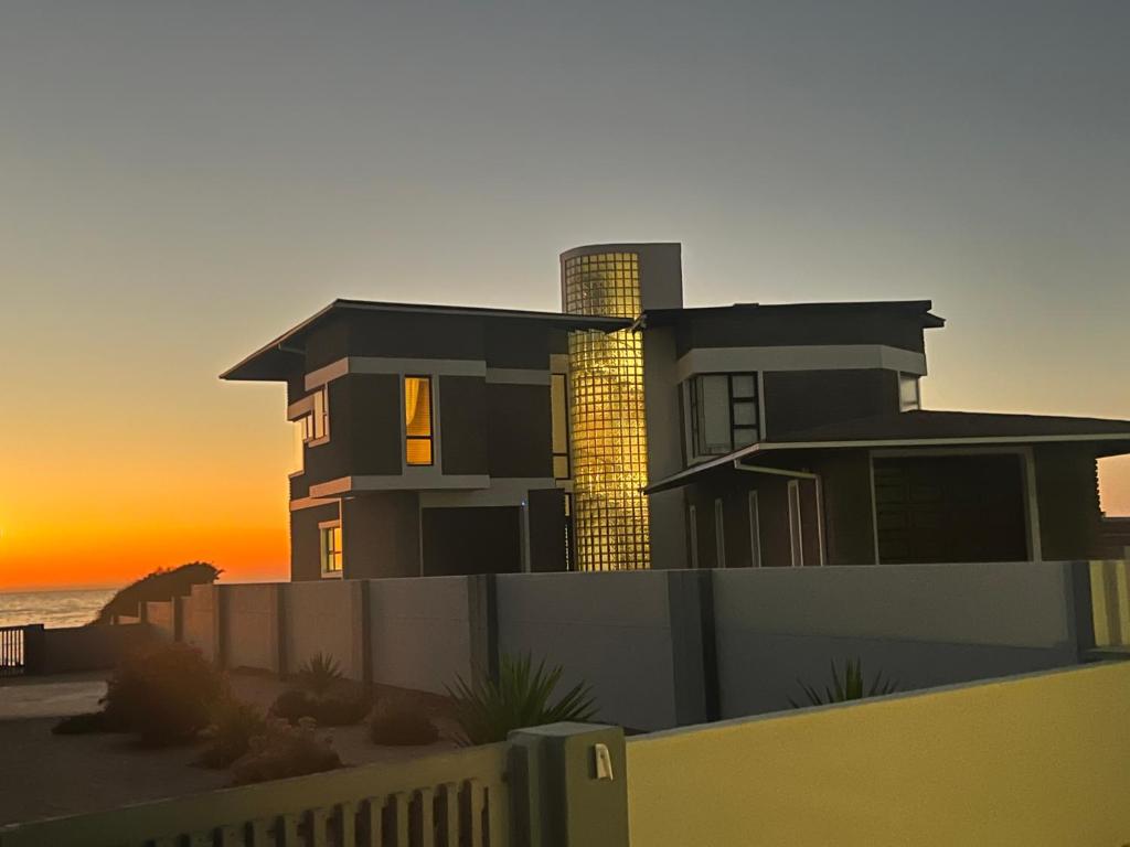 亨蒂斯湾Beach House的海滩上的房子,背景是日落