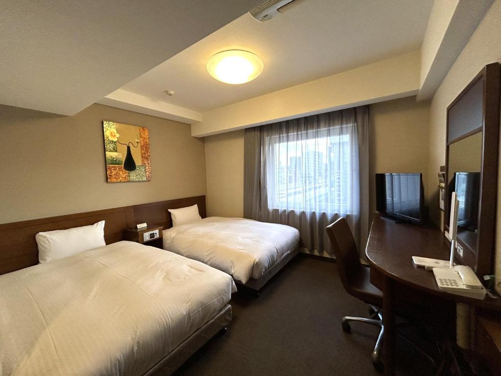 名古屋名古屋荣鲁泰因酒店的酒店客房设有两张床、一张桌子和一台电视。