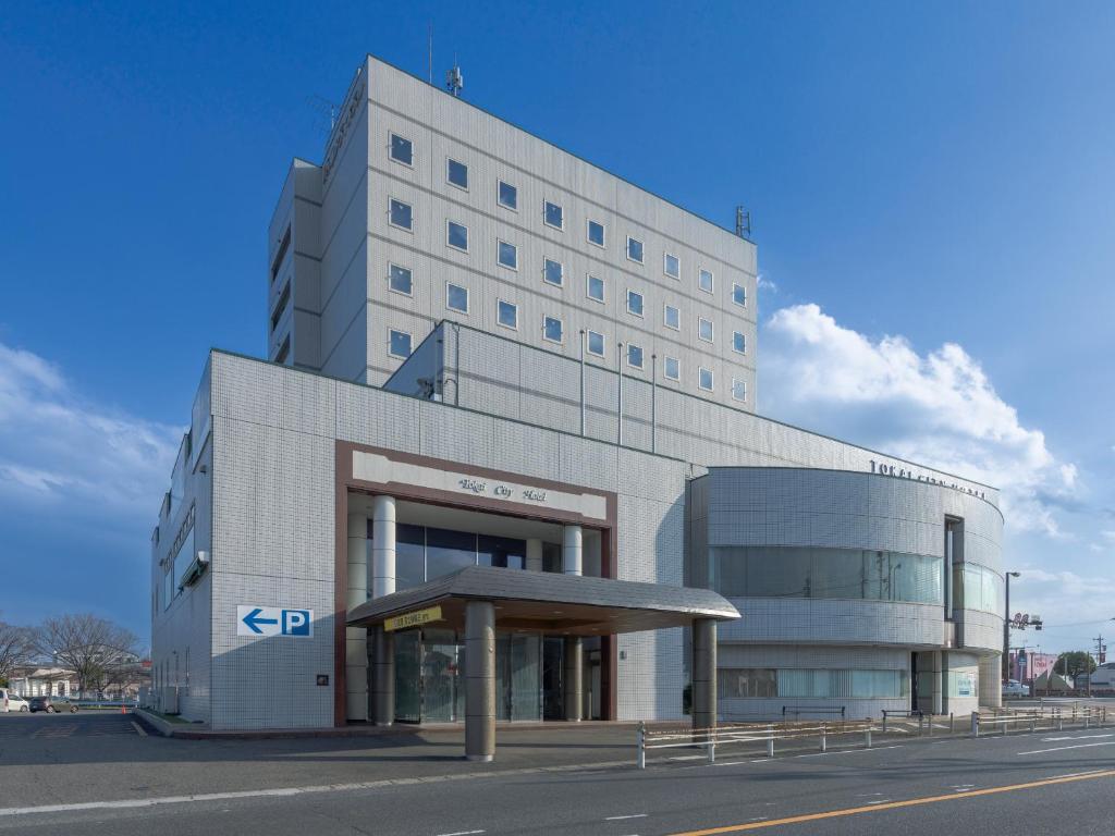 Tokai东海城市酒店的一座白色的大建筑,前面设有停车场