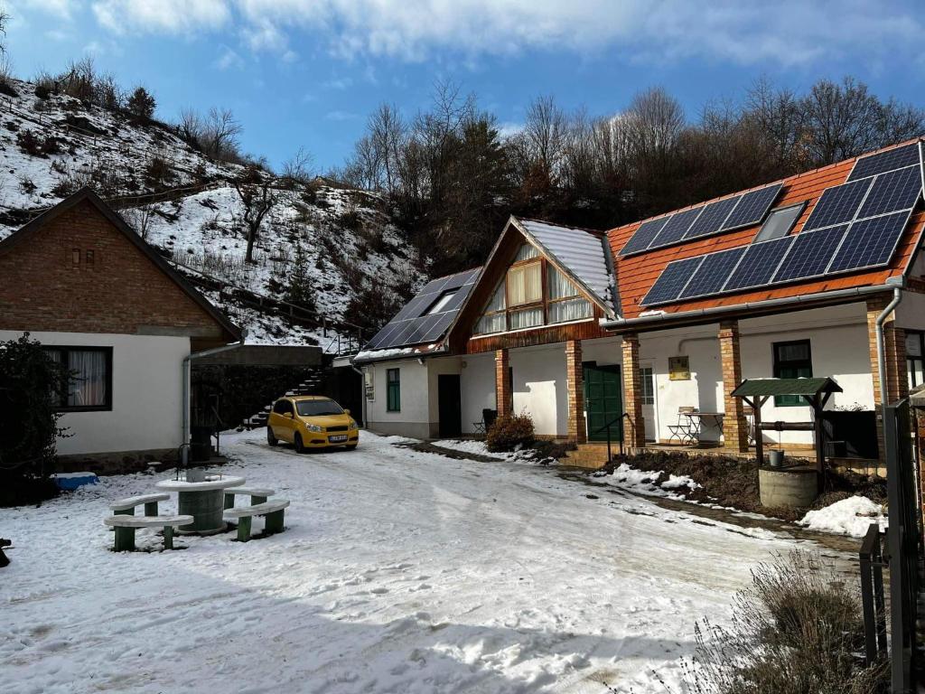 MatrakeresztesBoróka Vendégház的雪中屋顶上太阳能电池板的房子