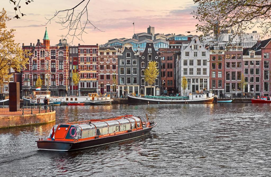 阿姆斯特丹Eden Hotel Amsterdam的城市中建有建筑物的河上的小船
