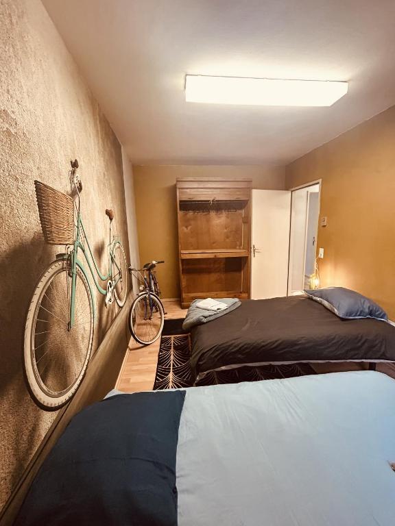 圣阿沃尔德LA MARIEFACTURE - Comme à Amsterdam的卧室配有两张床,墙上有一辆自行车