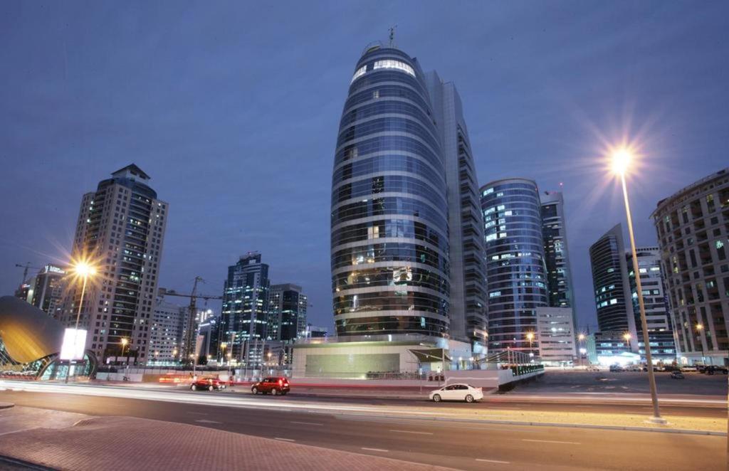 迪拜Citadines Metro Central Hotel Apartments的城市天际线,晚上有高楼