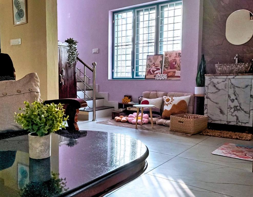 科钦KOVIL home's Guest land的客厅设有紫色墙壁和玻璃桌