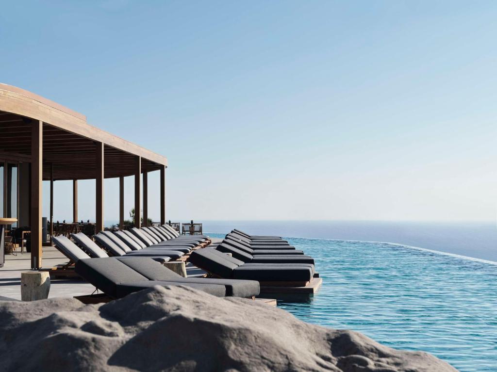 VourvoúlosMagma Resort Santorini, In The Unbound Collection By Hyatt的靠近大海的码头上的一排躺椅
