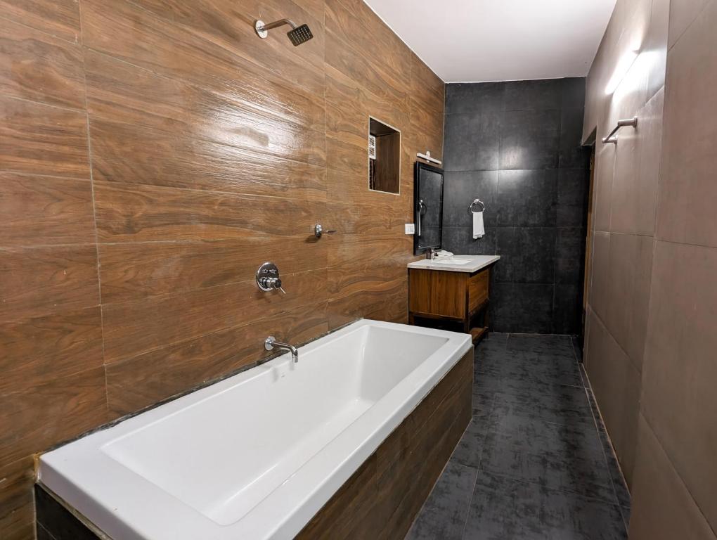 曼德姆Seaside Serenity Resort的一间带大型白色浴缸和木墙的浴室