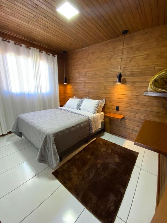 阿尔弗雷多瓦格内尔Aconchego Alto da Serra的一间卧室设有一张床和木墙