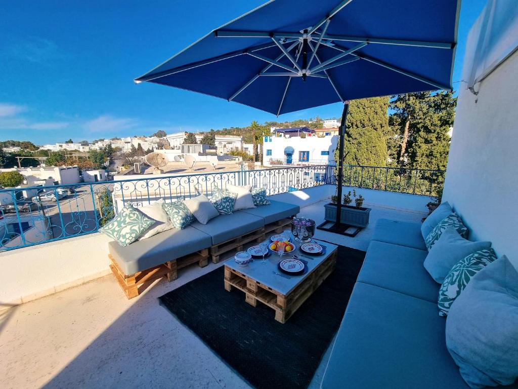Dar Mimoun BeyLe Superbe - Sidi Bou Saïd的阳台配有蓝色的沙发和带雨伞的桌子
