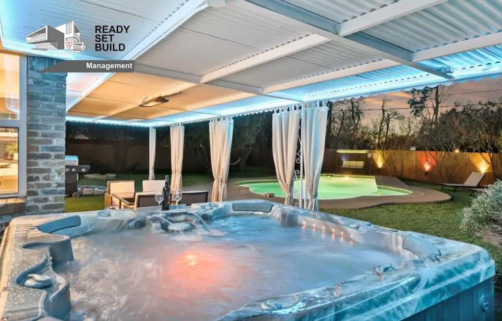 法默斯布兰奇DFW Lux House with Huge Backyard Pool Jacuzzi Bbq Cinema etc的庭院内的热水浴池和天井