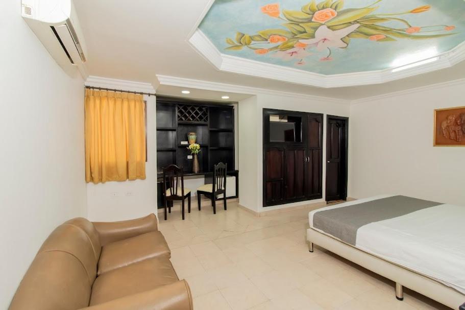 巴兰基亚Hotel Caribe Plaza Barranquilla的一间卧室配有一张床、一张沙发和一张桌子