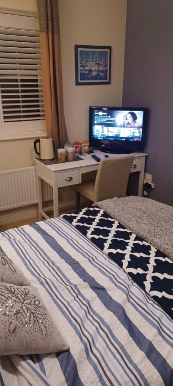 BuckinghamshireAylesbury Lovely Double and Single Bedroom with Guest only Bathroom的一间卧室配有一张床和一张书桌及电视