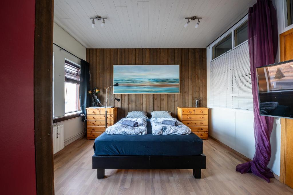 Stokkseyri艺术旅舍的一间卧室配有一张带蓝色床单和木墙的床。