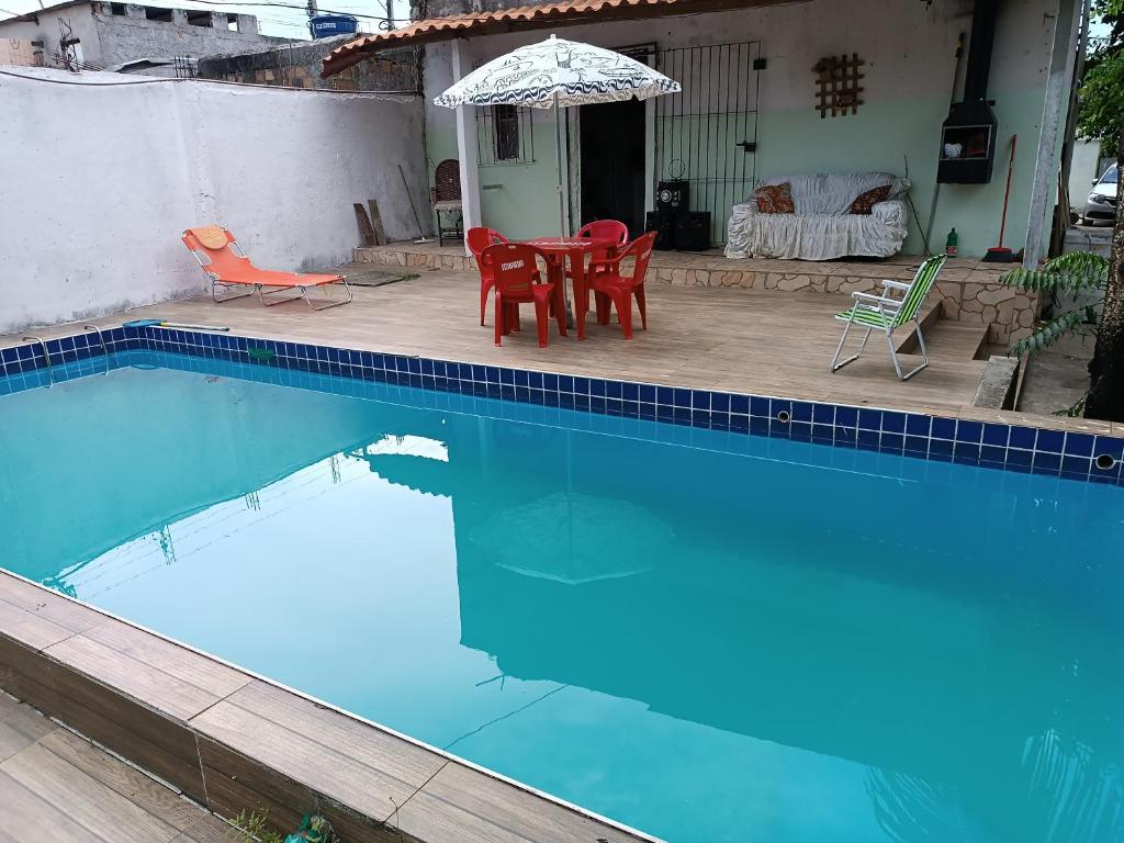 伊塔帕里卡Casa na ilha de Itaparica的一个带桌椅和遮阳伞的游泳池