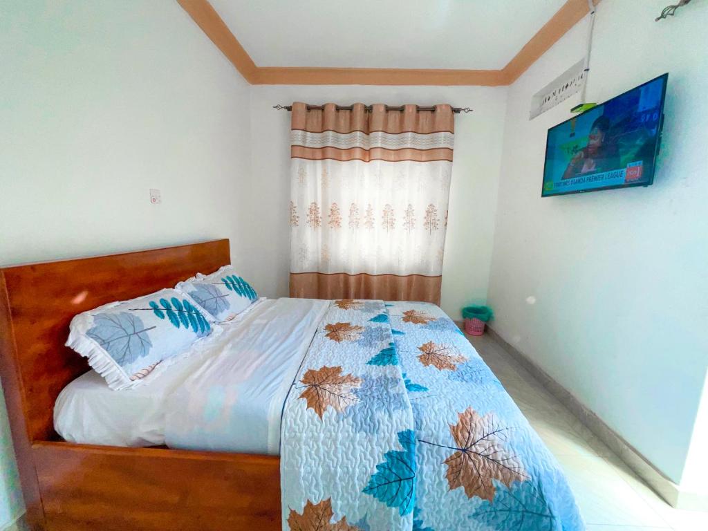 KisoroAgape House的一间卧室配有一张带蓝色棉被的床