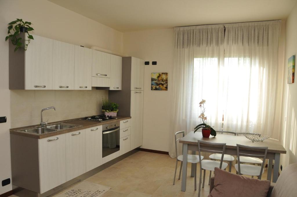 佩斯基耶拉德加达湖泊公寓的厨房配有白色橱柜和桌椅