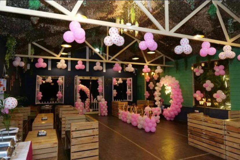 德拉敦The Bluewind Resort的充满了粉红色花卉和木桌的房间