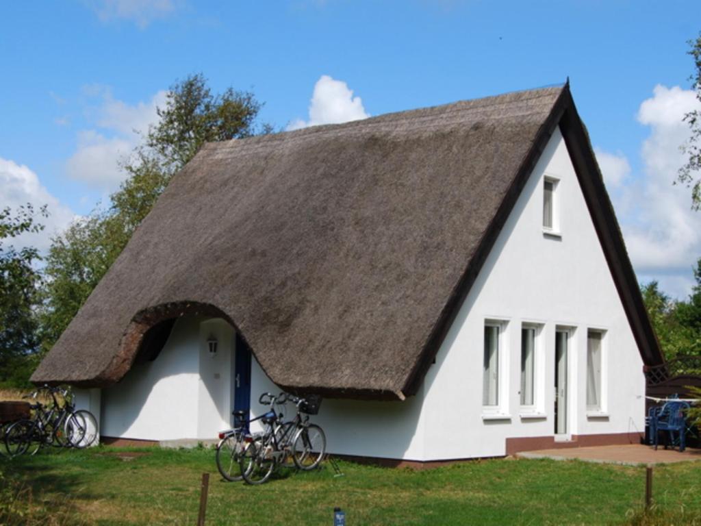 维特Doppelhaushälfte in Vitte auf Hiddensee的茅草屋顶的房子,外面有自行车停放处