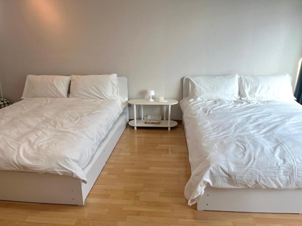 首尔Hongik univ station Exit 1的一间卧室配有两张带白色床单和桌子的床
