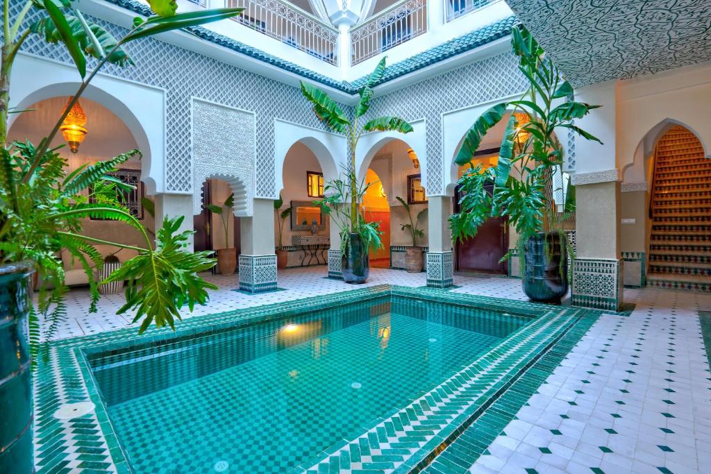 马拉喀什BÔ Riad Boutique Hotel & Spa的一座棕榈树建筑中的室内游泳池
