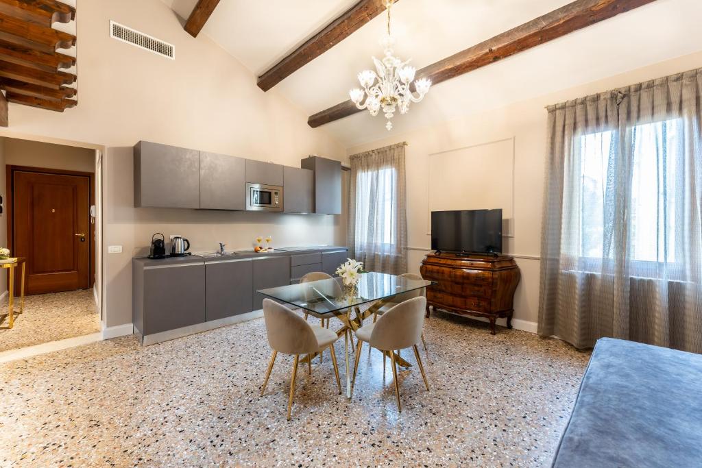 威尼斯San Vio Palace Luxury Apartments的厨房以及带玻璃桌和椅子的用餐室