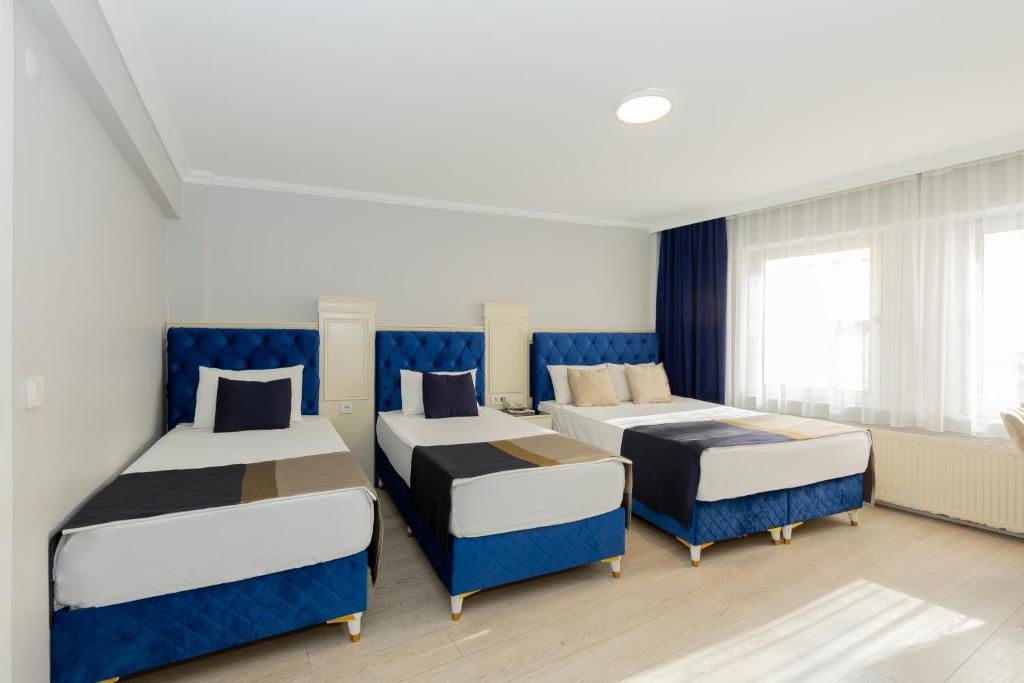 伊斯坦布尔Sirkeci Grand Family Hotel & SPA的带三张床和蓝色椅子的房间