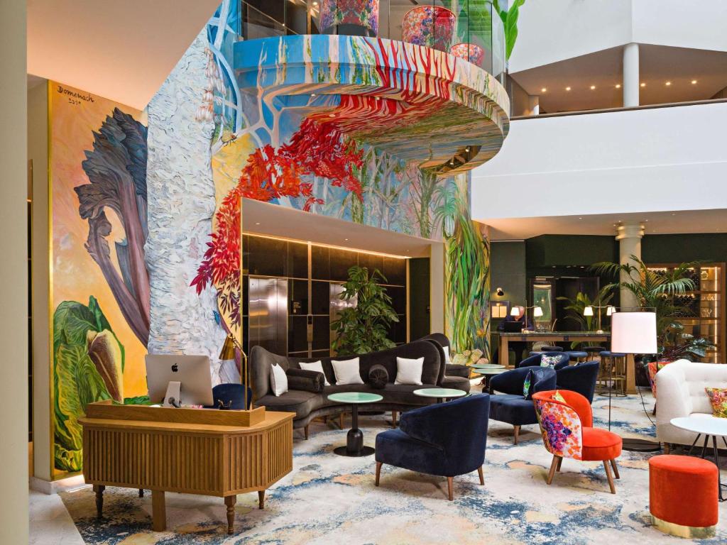 布鲁塞尔布鲁塞尔欧洲索菲特酒店的大堂配有沙发、椅子和壁画