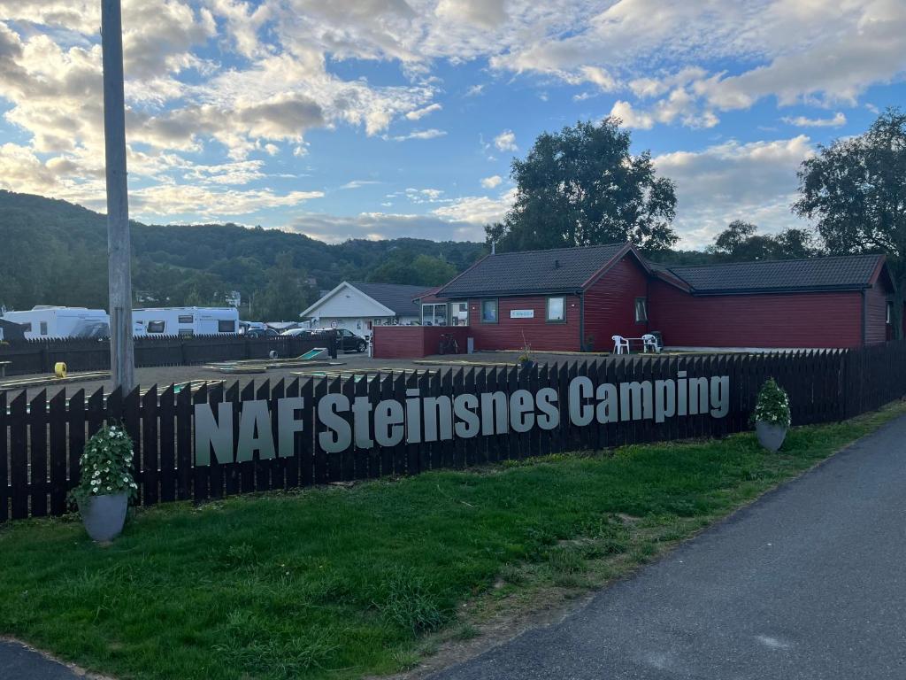 埃格尔松NAF Steinsnes Camping的红谷仓旁的栅栏上的标志