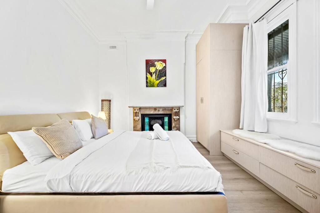悉尼Modern 4B2B house@Glebe的白色卧室设有一张大床和一个壁炉