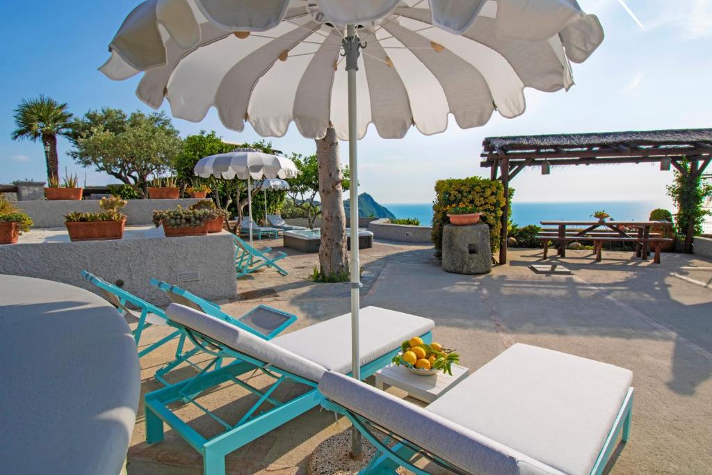伊斯基亚Villa Titina - Sunset Apartments的海滩上遮阳伞下的桌椅