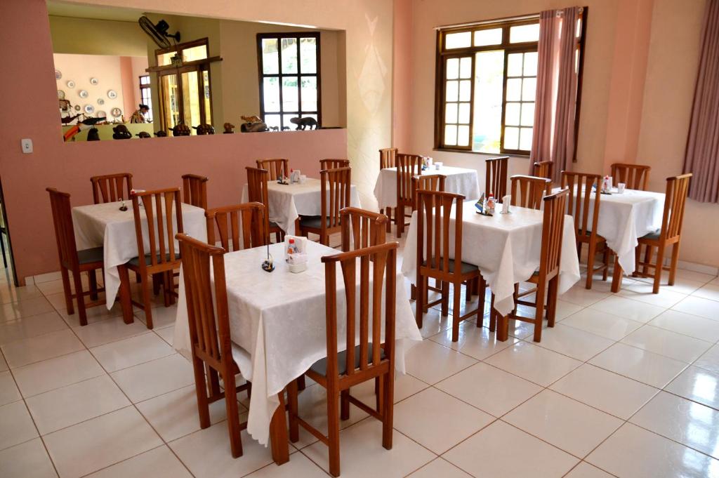 阿尔特杜尚Pousada Cabocla的用餐室配有白色的桌子和木椅