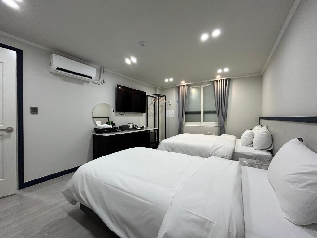 木浦市Hotel Bom的酒店客房设有两张床和电视。