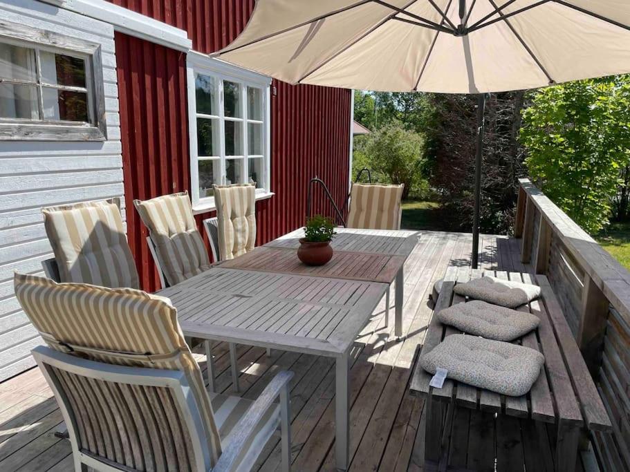 韦斯特维克Mysigt hus för 2 familjer的甲板上配有一张木桌和椅子及遮阳伞