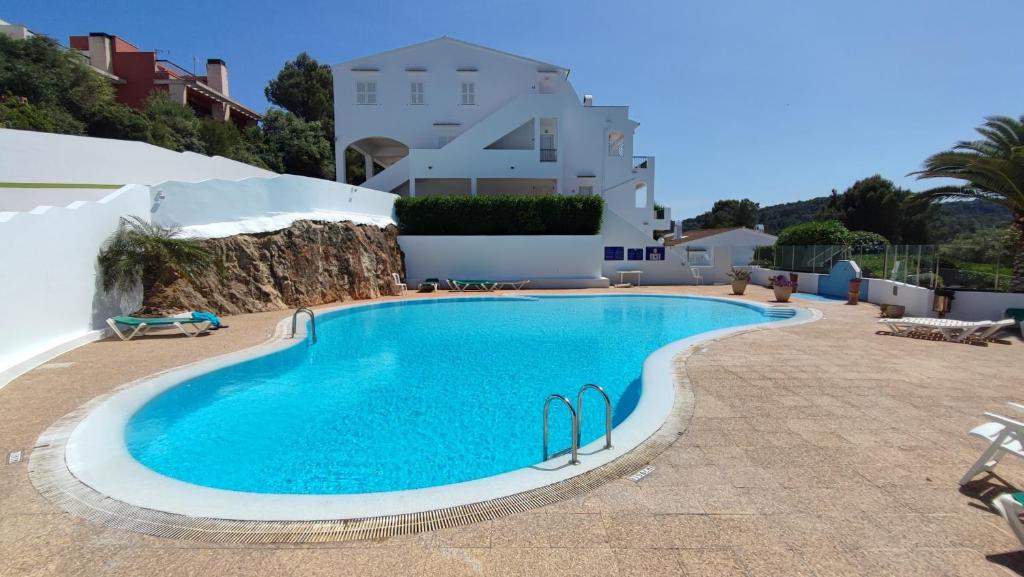 桑帕克Apartamento en el campo de golf Son Parc, Menorca的白色建筑前的大型游泳池