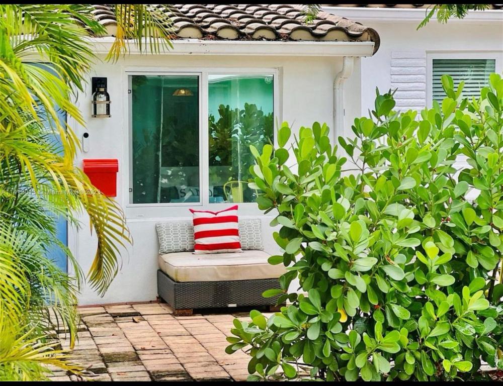 劳德代尔堡Private Fort Lauderdale cottage的门廊配有带红色和白色枕头的长凳