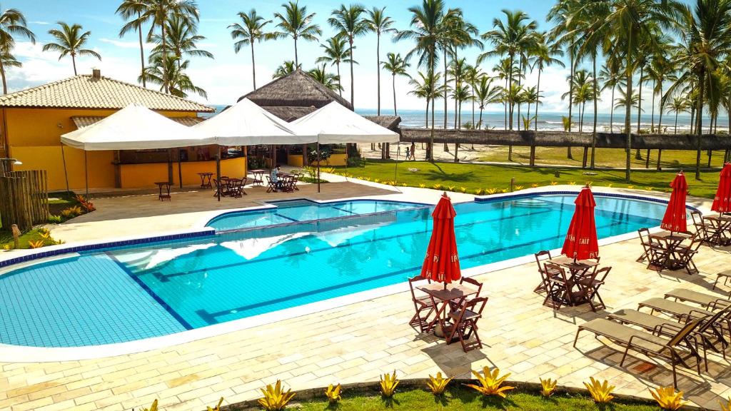 卡纳维埃拉斯Makaira Beach Resort的一个带椅子和遮阳伞的游泳池以及大海