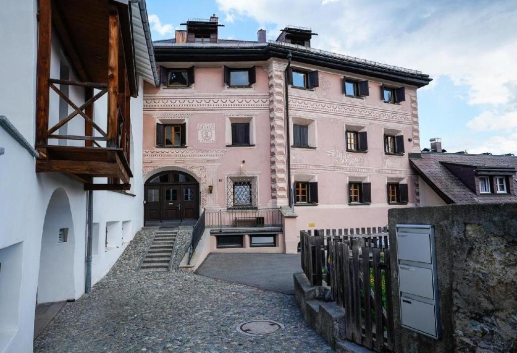 萨梅丹Chesa Fischer Wohnung Palü ÖV-Inklusive的一座粉红色的建筑,前面有一个门