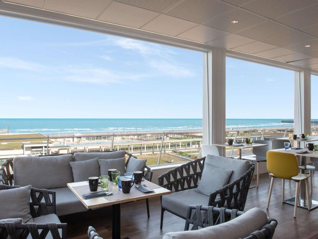 迪耶普迪耶普美居公寓酒店的一间带桌椅的海景餐厅